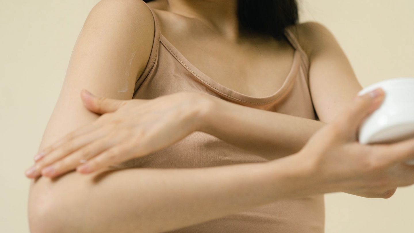 목과 팔꿈치 안쪽 피부에 보습제를 바르는 성인의 손