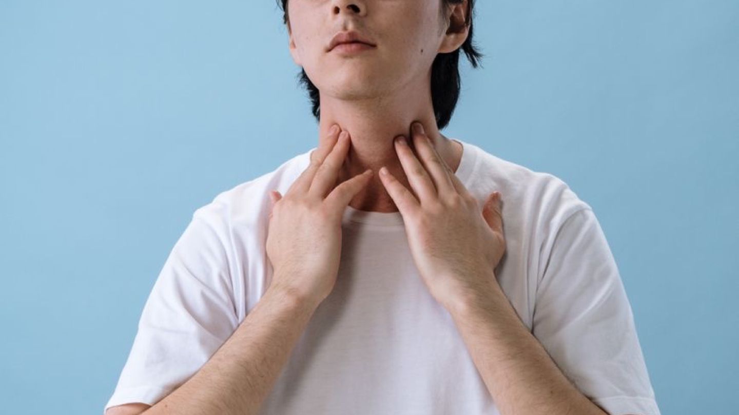 목의 이물감을 느끼며 손으로 목을 감싸는 사람