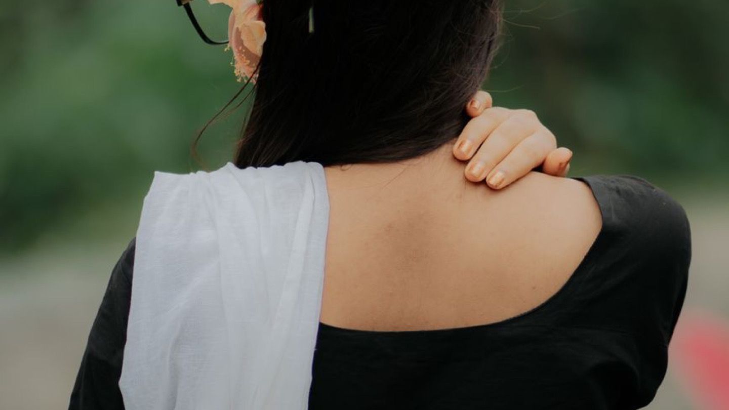 어깨 통증을 느끼는 장면을 떠올리게 하는 사진(뒷모습만 보임, 환자 얼굴·약병·상표 없음, 의료진처럼 보이는 사람 없음)