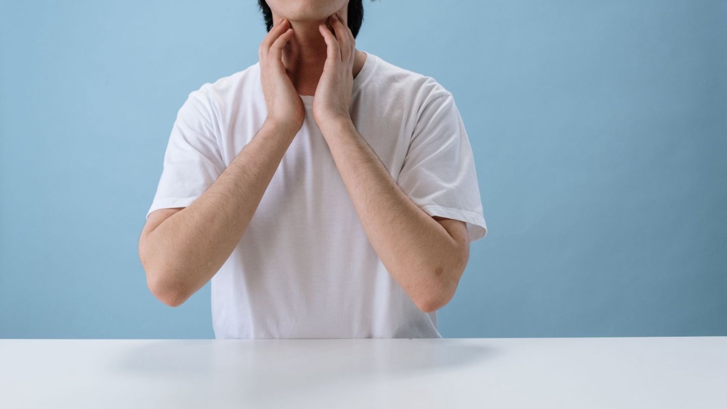 목이 따가워 손으로 목을 감싸 쥔 사람
