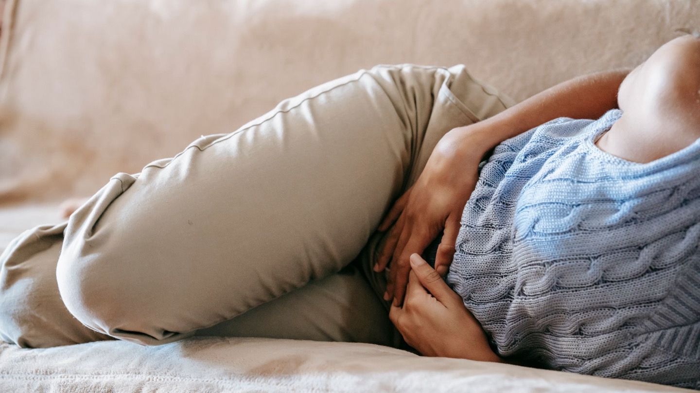 아침에 일어나 침대에 걸터앉아 배를 만지는 사람의 뒷모습