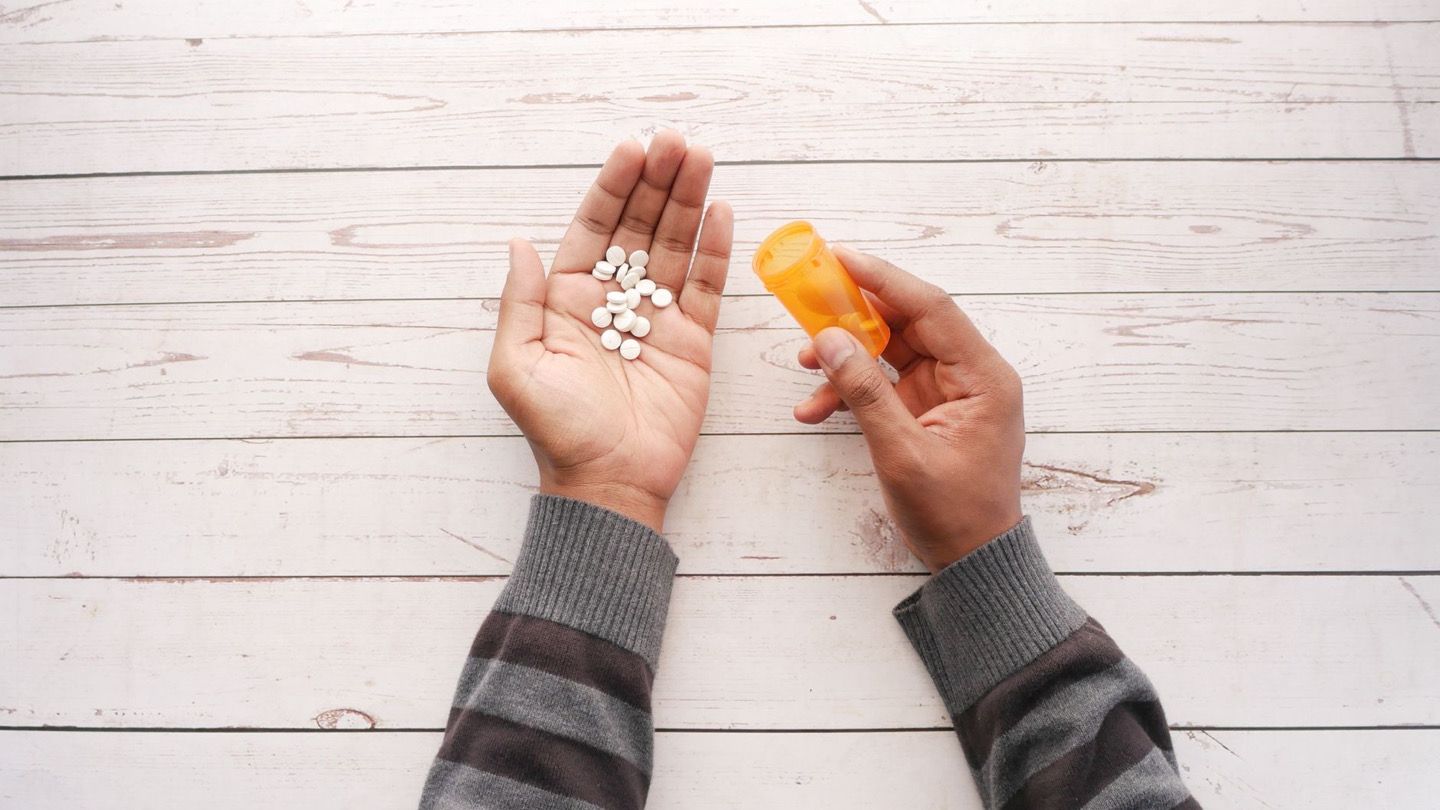 person reading medicine leaflet with multiple pill bottles