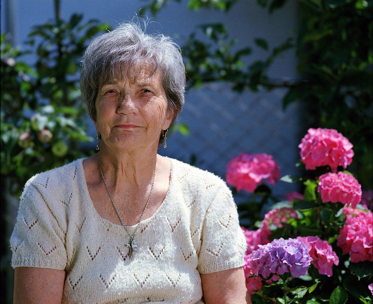 집 밖에 앉아 있는 고령 여성